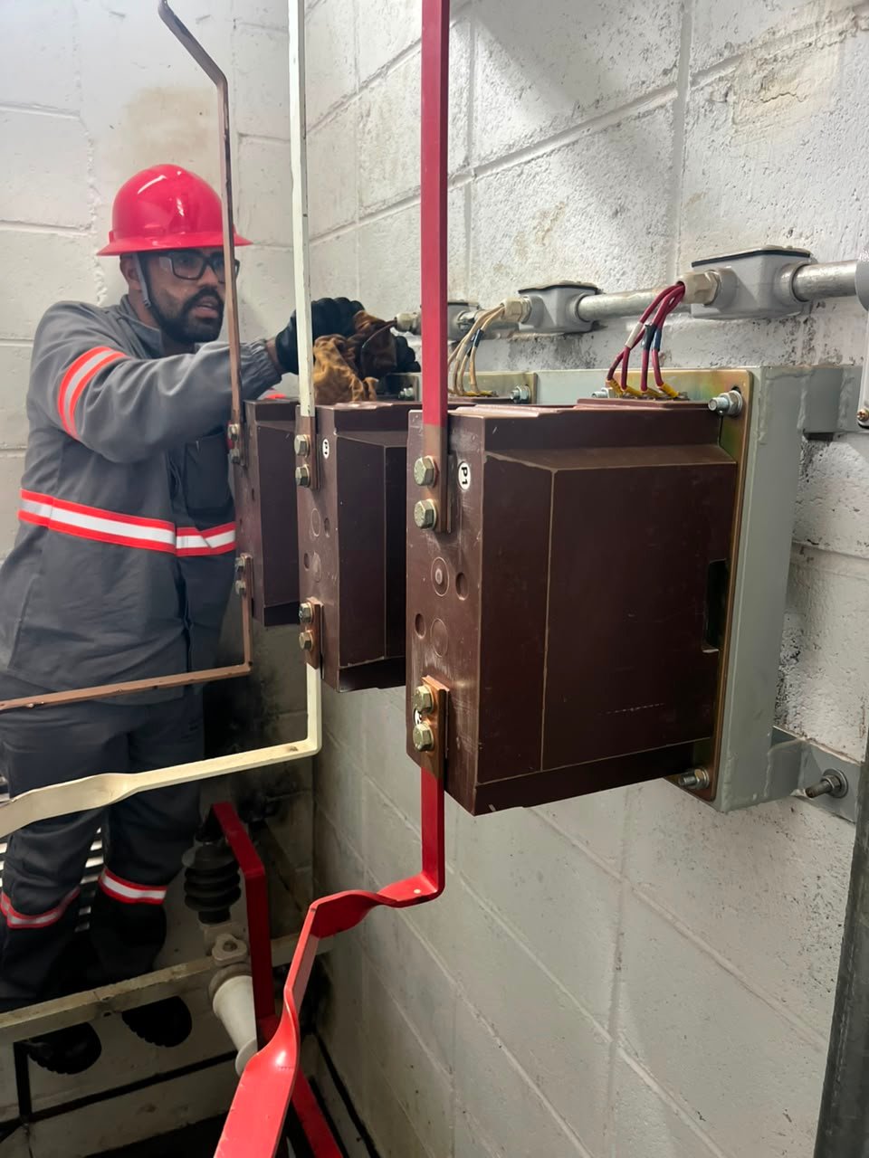 Eletricista da IND FORÇA operando chave seccionadora em cabine de medição